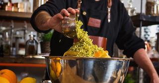 Lemon and orange zest is thrown into a large metallic mixing bowl 