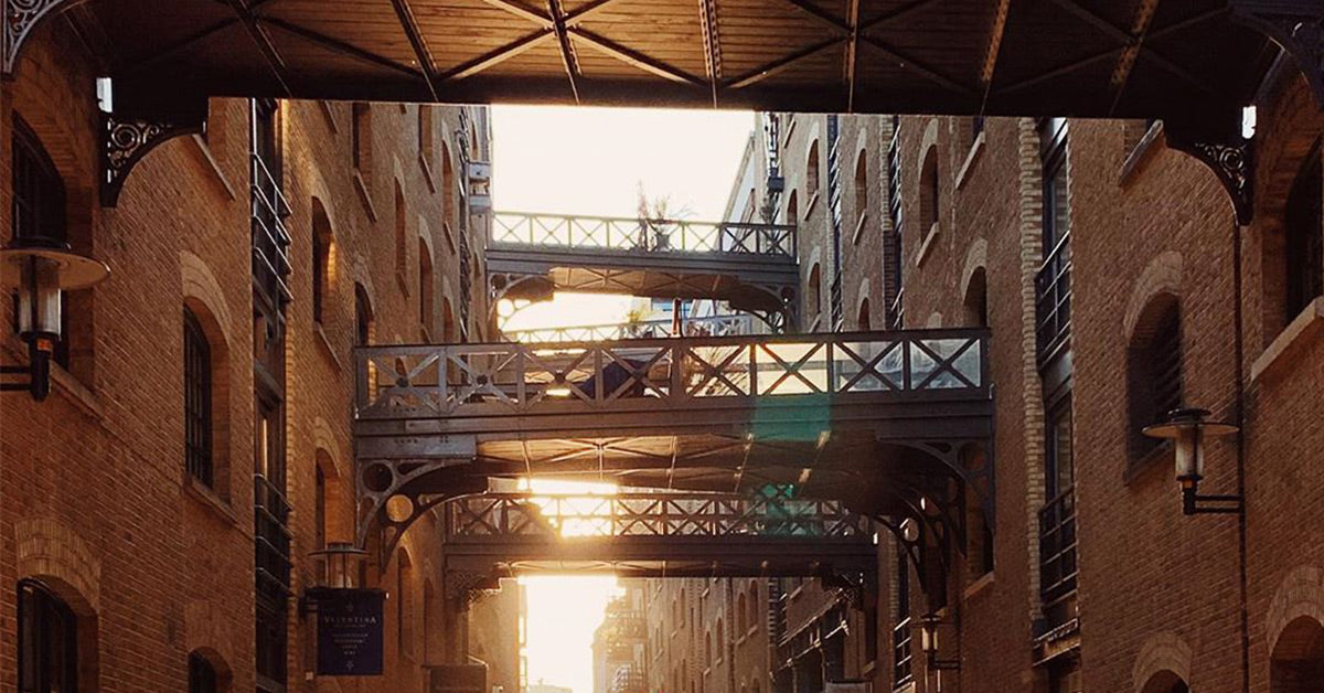 The rising sun lights several bridges connecting old warehouses inShad Thames, London