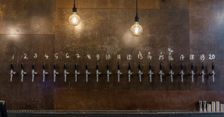 20 beer taps at brick brewery taproom underneath two dangling lightbulbs