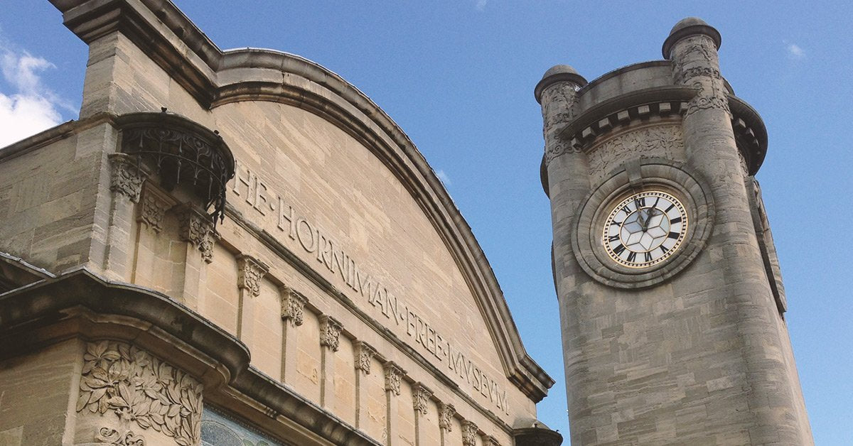 A clock tower and frontage to the Horniman Museum against a blue sky